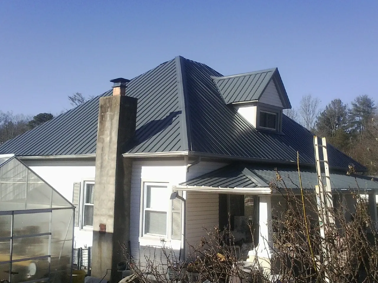 Dark blue standing seam metal roof on a white farmhouse with dormer — Slate & Tile Roof Repair by Roofing Brothers in Rantoul