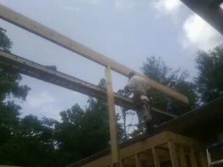 Carpenter setting a ridge beam over a new addition frame — Ice Dam Removal by Roofing Brothers in Rantoul