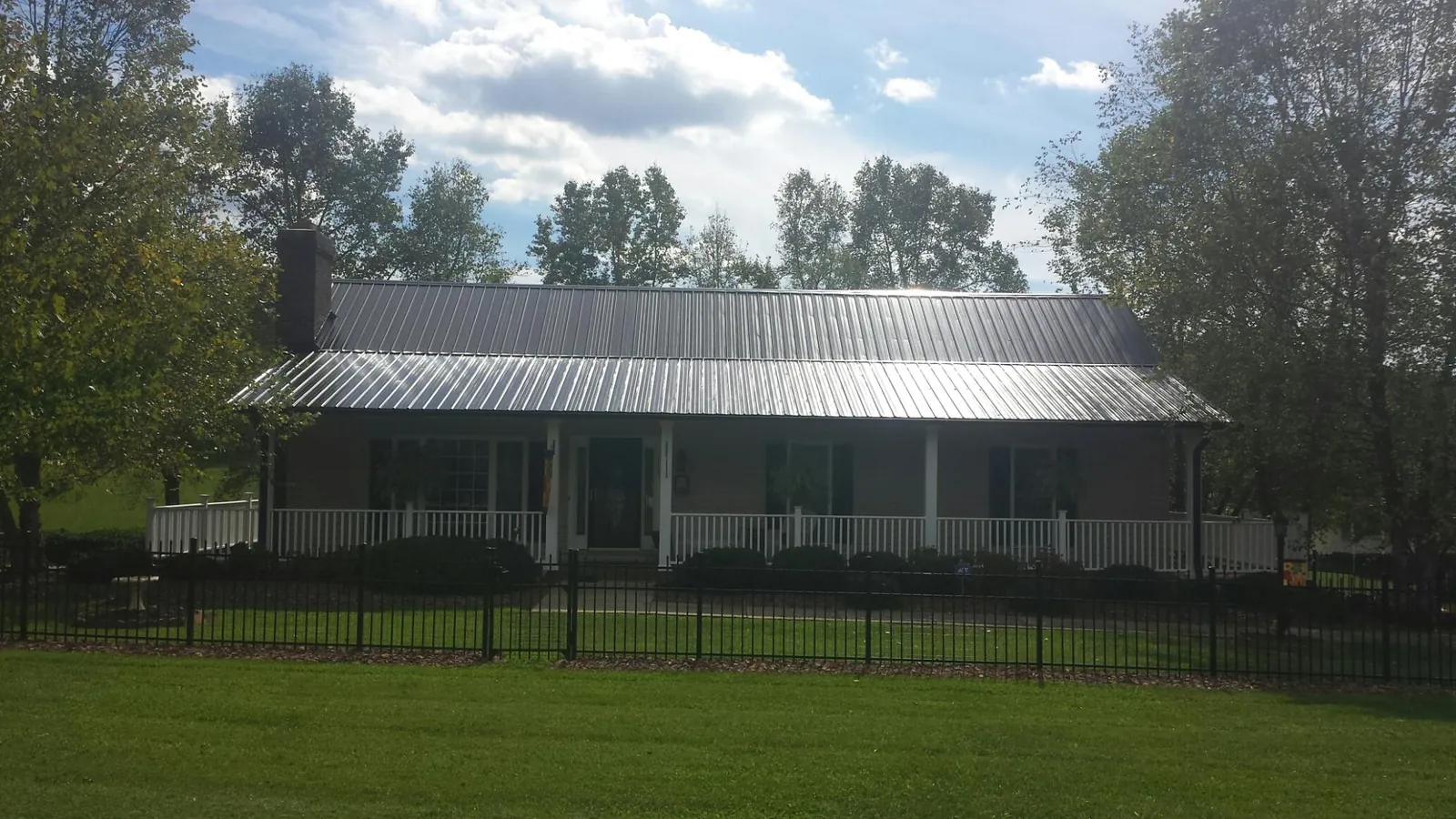 Gray metal roof on a brick ranch with a full width front porch — Gutter Guard Installation work by our crew in Rantoul